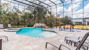 An indoor swimming pool with a waterfall feature, surrounded by lounge chairs and a covered patio area. - Grhval8172 - Reunion Resort - 8 Bed 8 Baths House (Kissimmee)