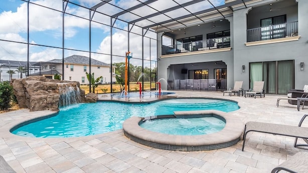 A pool area with a hot tub, a waterfall feature, and outdoor seating.