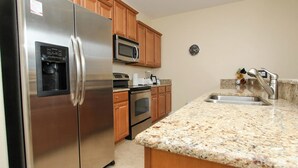 A kitchen with stainless steel appliances, wooden cabinets, granite countertops, and a built-in microwave. - Grhbch3069 - Paradise Palms Resort - 4 Bed 3 Baths Townhouse (Kissimmee)
