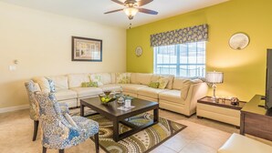 A living room with a beige sofa, patterned armchairs, a coffee table, and a TV. - Grhcal8951 - Paradise Palms Resort - 5 Bed 4 Baths Townhouse (Kissimmee)