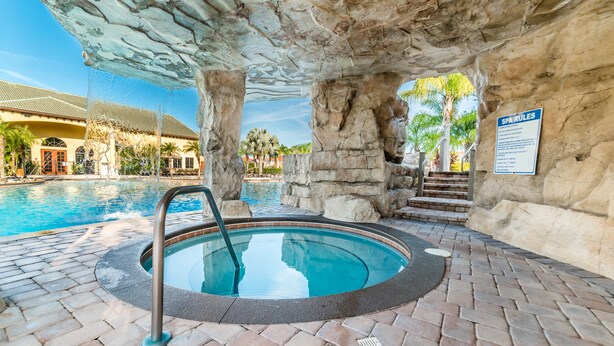 A hot tub with a stone arch overhead, a pool in the background, and a sign labeled "SPA RULES". - Grhcal8951 - Paradise Palms Resort - 5 Bed 4 Baths Townhouse (Kissimmee)