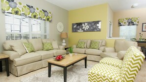 A living room with two beige sofas, a wooden coffee table, and a yellow armchair. - Grhmap8980 - Paradise Palms Resort - 5 Bed 4 Baths Townhouse (Kissimmee)