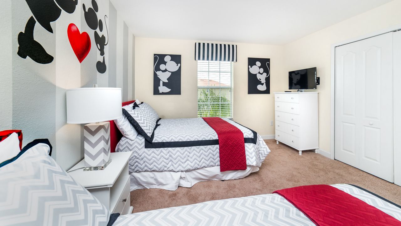 A bedroom with a bed, bedside tables, a dresser, a TV, and wall art.