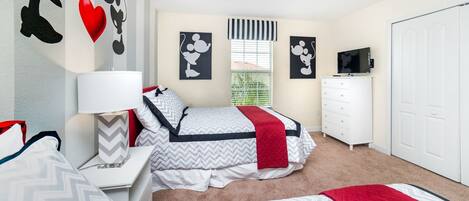 A bedroom with a bed, bedside tables, a dresser, a TV, and wall art.