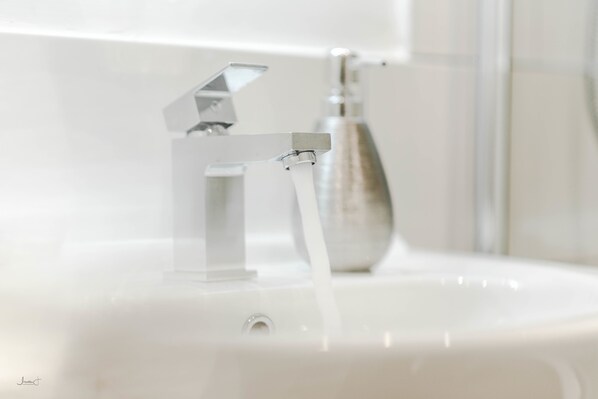 A modern bathroom sink with a chrome faucet and clear water running.