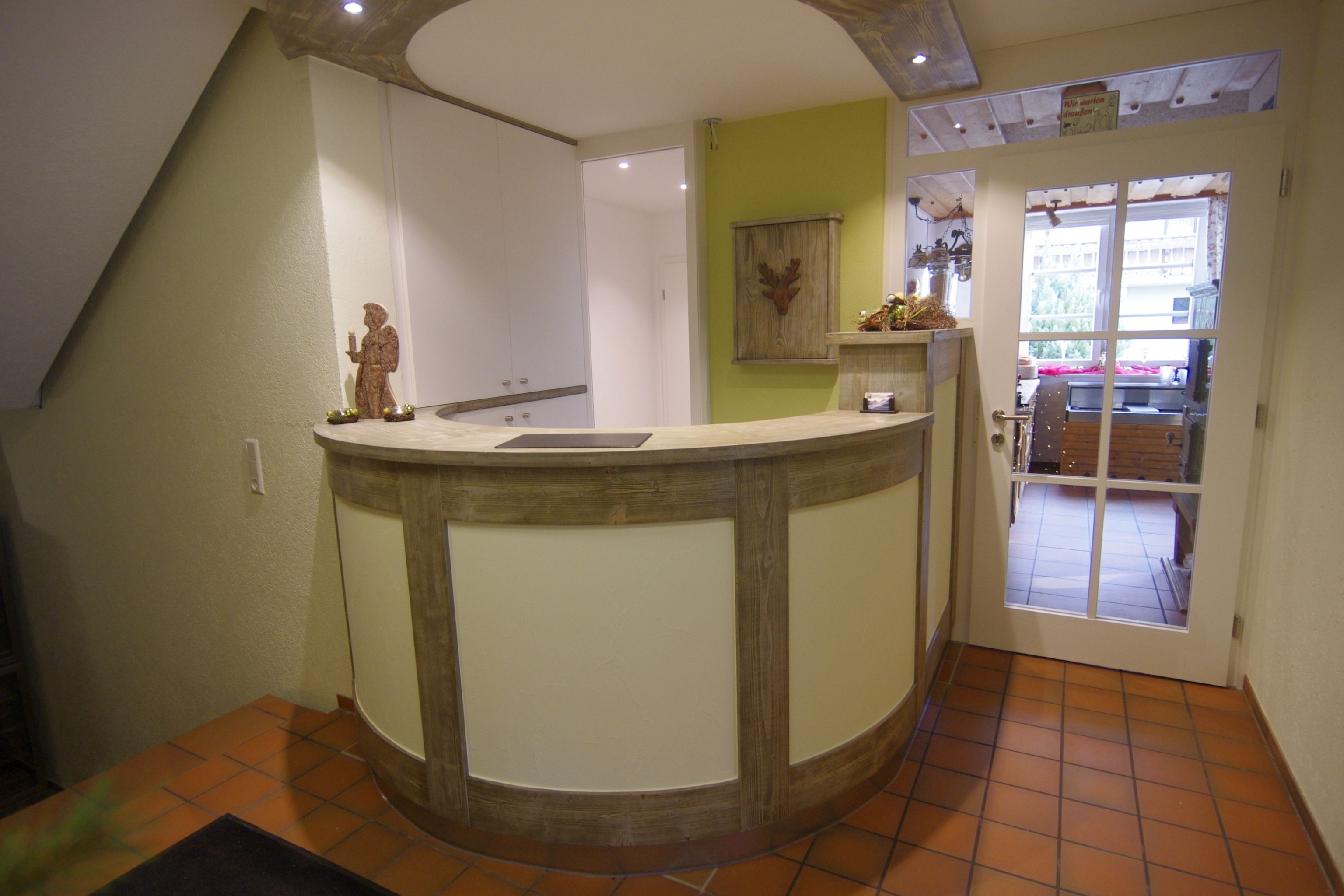 A reception area with a curved counter, a statue, and a view through a glass door to an outdoor space.