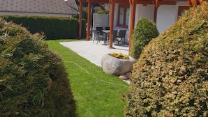 Une maison dotée d’une terrasse en bois, d’un patio avec mobilier d’extérieur et d’une pelouse bien entretenue.