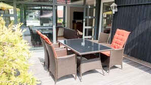 An outdoor patio with wicker furniture, a glass table, and a view of the surrounding area. - Pension Böttger (Wernigerode)