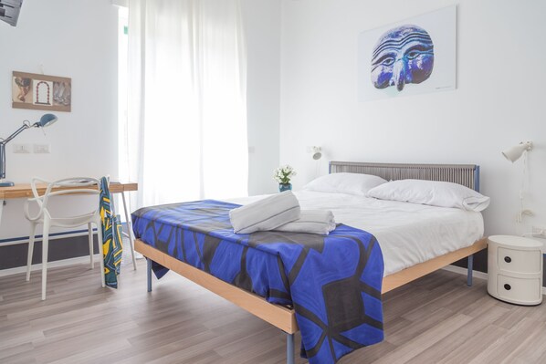 Un dormitorio con cama, escritorio, silla y mesita de noche.