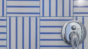 Une salle de bain avec un mur recouvert de carreaux présentant un motif à rayures bleues et blanches.