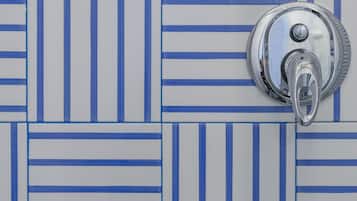 Casa de banho com parede revestida de azulejos com padrão azul e branco listrado.