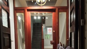 Uma porta de madeira com um painel de vidro, uma placa com o número 78 acima e um tapete na entrada.