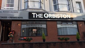 Um hotel chamado "The Orbiston", com uma placa de identificação, um endereço de site e um número de contato.