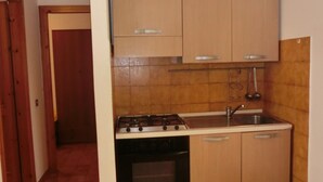 Cocina compacta con muebles de madera, estufa a gas, horno y lavamanos.