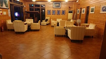 Cómoda sala de estar con suelo de madera, varios sillones blancos y una mesita.