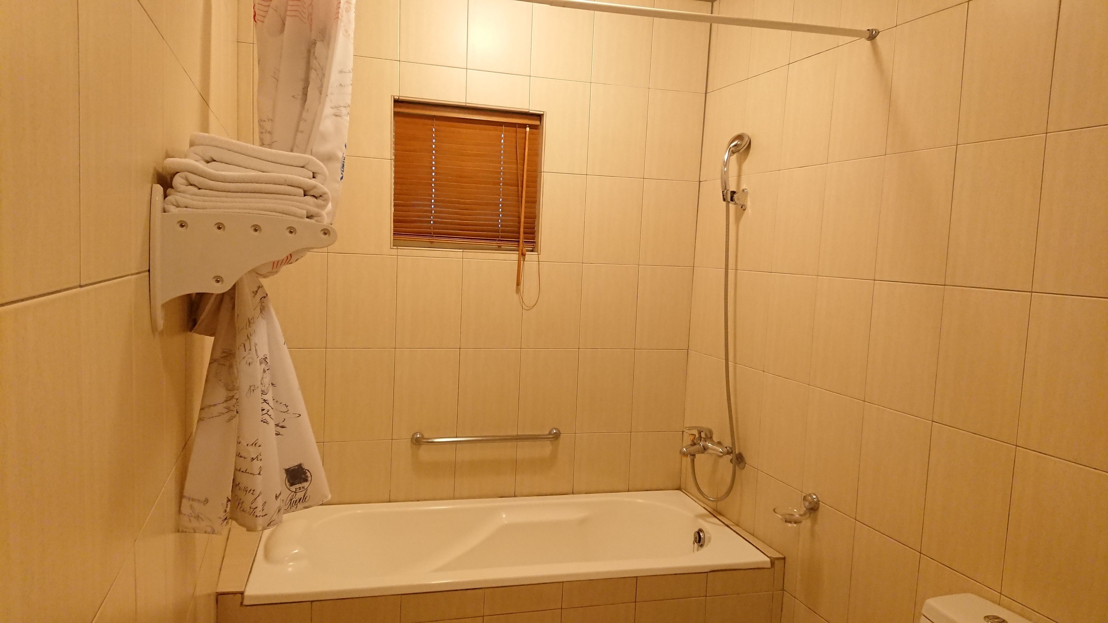 A bathroom with a bathtub, a shower, and a towel rack with folded towels.
