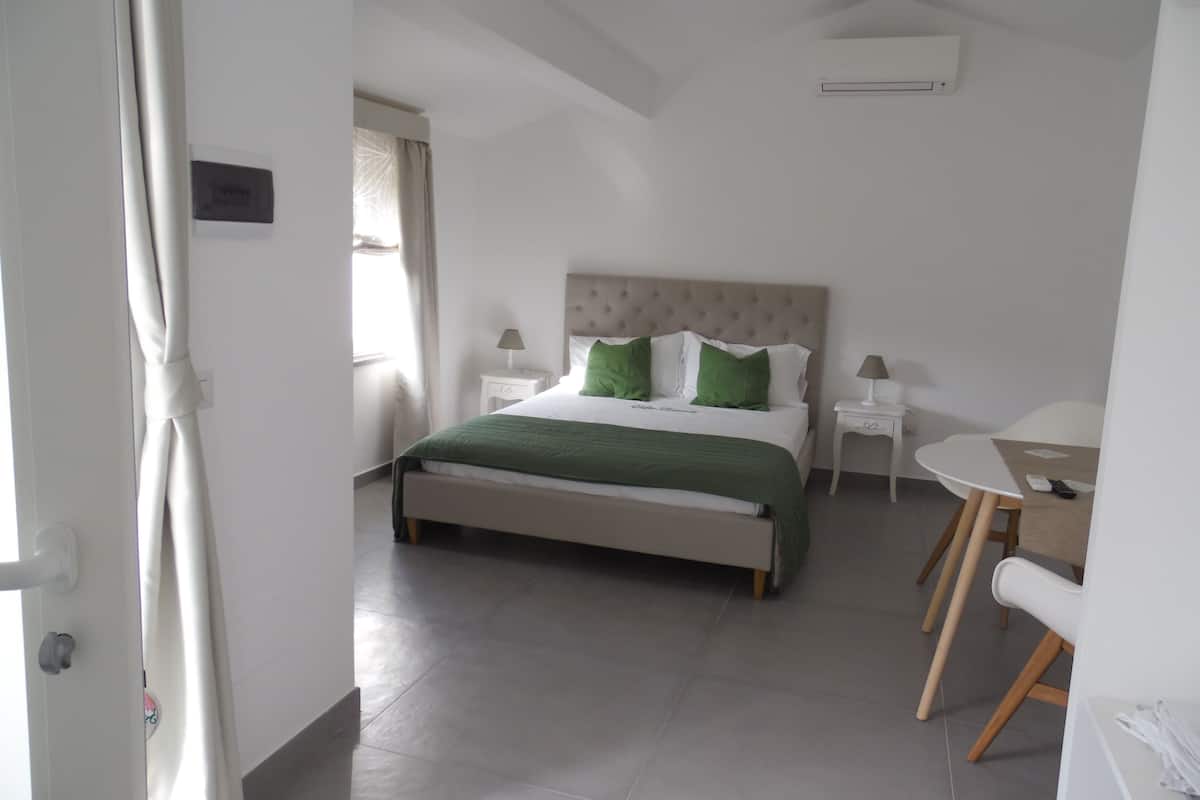 Ein Schlafzimmer mit einem Bett, Nachttischen, einem Sessel und einem kleinen Tisch.