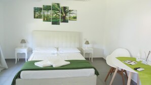 A hotel room with a bed, a desk, and a chair. There are three wall-mounted paintings above the bed. - Villa Bianca (Castellammare di Stabia)