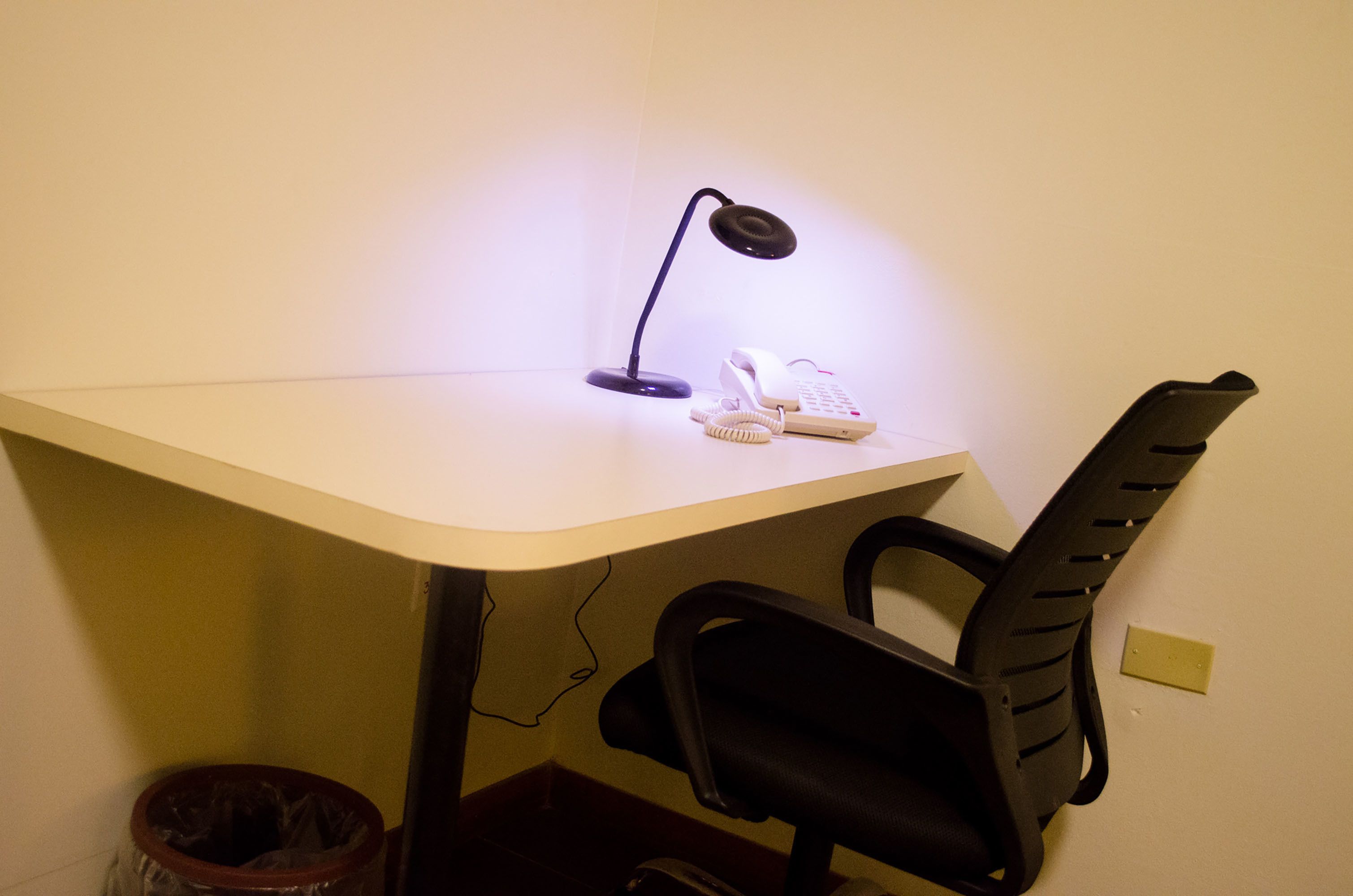 A desk with a lamp, a telephone, and a chair.
