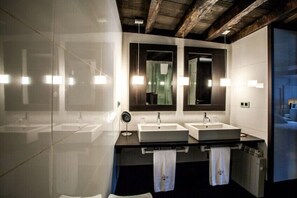 Un baño moderno con dos lavamanos, espejos grandes y luces colgantes.