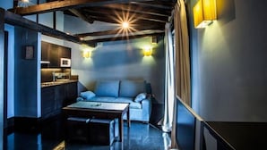 Un salon chaleureux avec un canapé, une table basse et un téléviseur. Des lampes sont fixées aux murs et le plafond est en bois.