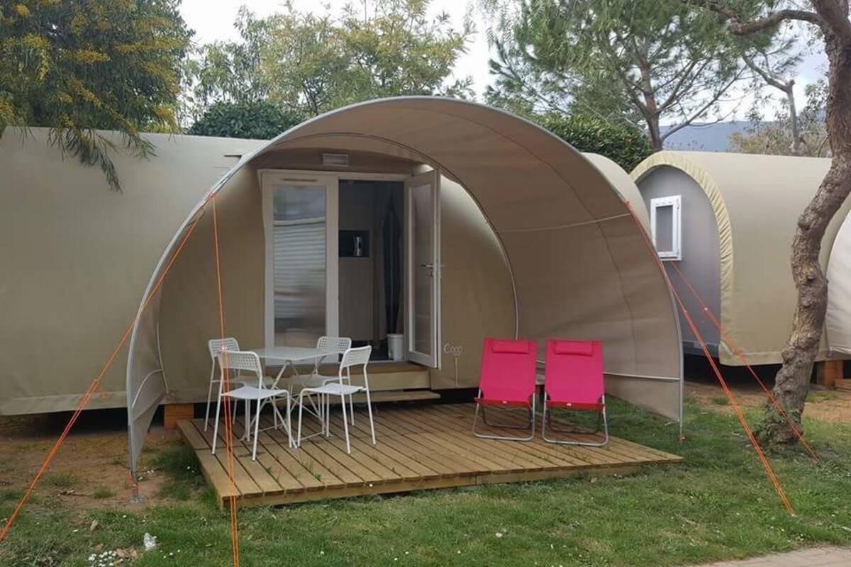 Une tente portative, avec une table et des chaises installées sur une terrasse en bois.