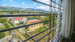 A view from a window overlooking a town with buildings and mountains in the distance.