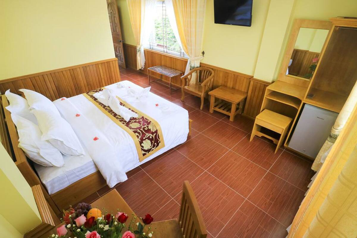 Une chambre d’hôtel avec un lit, un bureau, une chaise et un téléviseur.