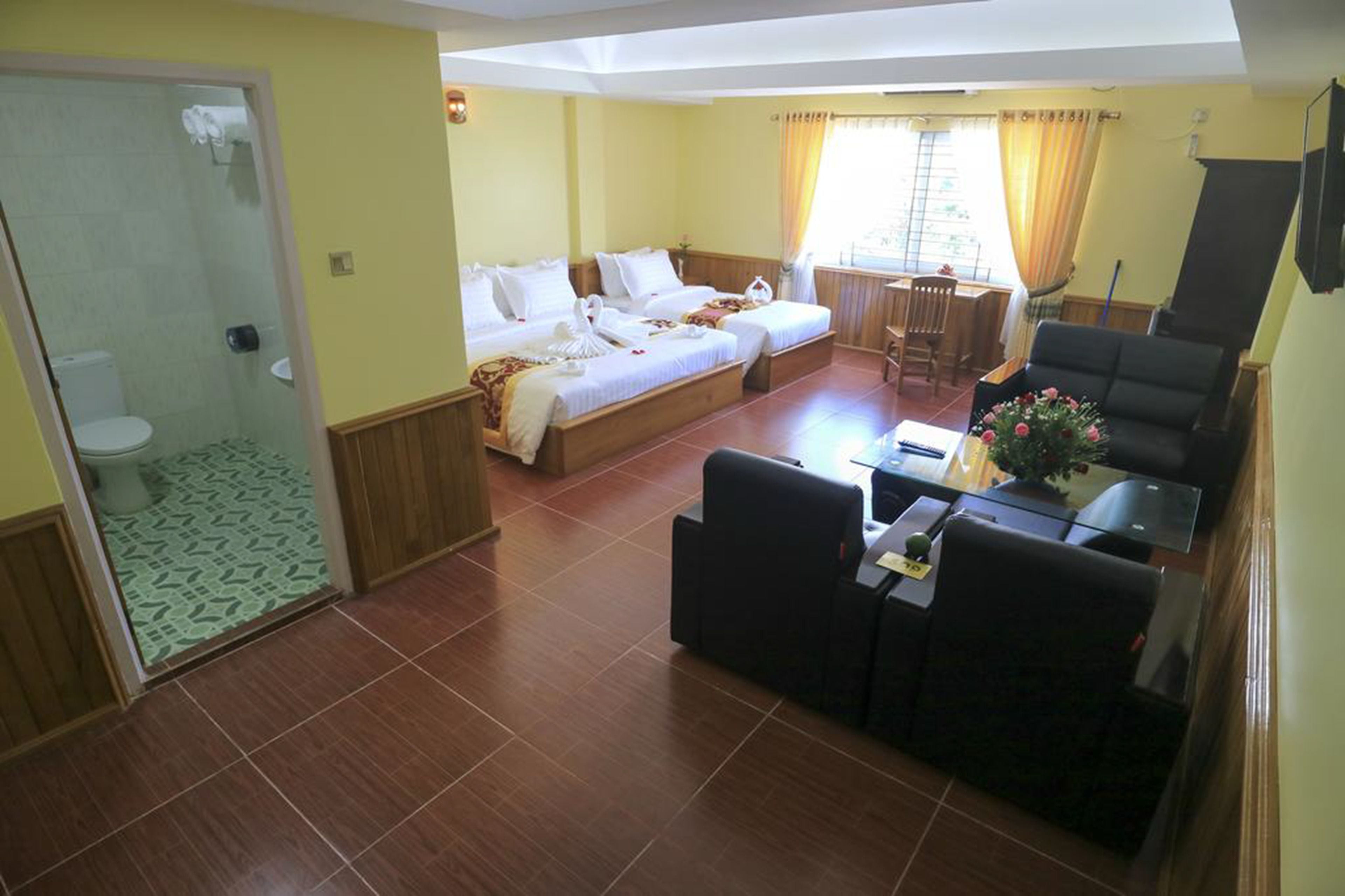A hotel room with two beds, a small dining area, and a seating area.