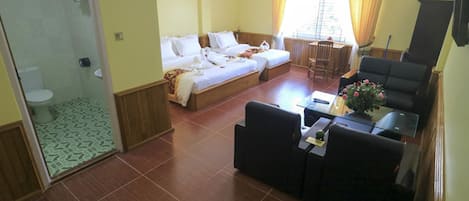 A hotel room with two beds, a small dining area, and a seating area.