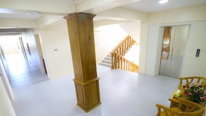 A spacious lobby with a wooden column, a staircase, and a reception area with a desk and chairs.