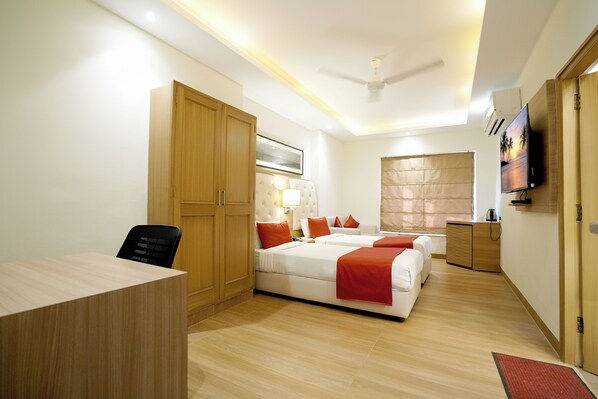 A hotel room with a desk, two beds, a wardrobe, a television, and a ceiling fan. - Kalinga Hotel (Jodhpur)