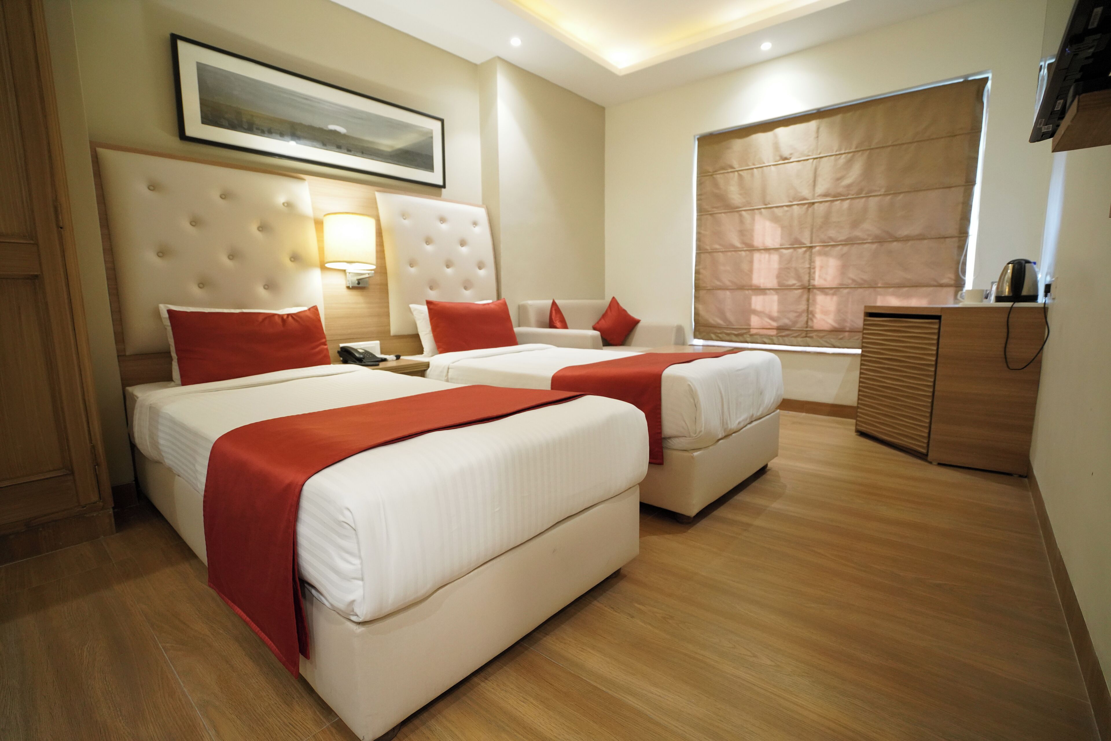 Habitación de hotel con dos camas, un ventanal con vistas, televisión y un mueble de madera.