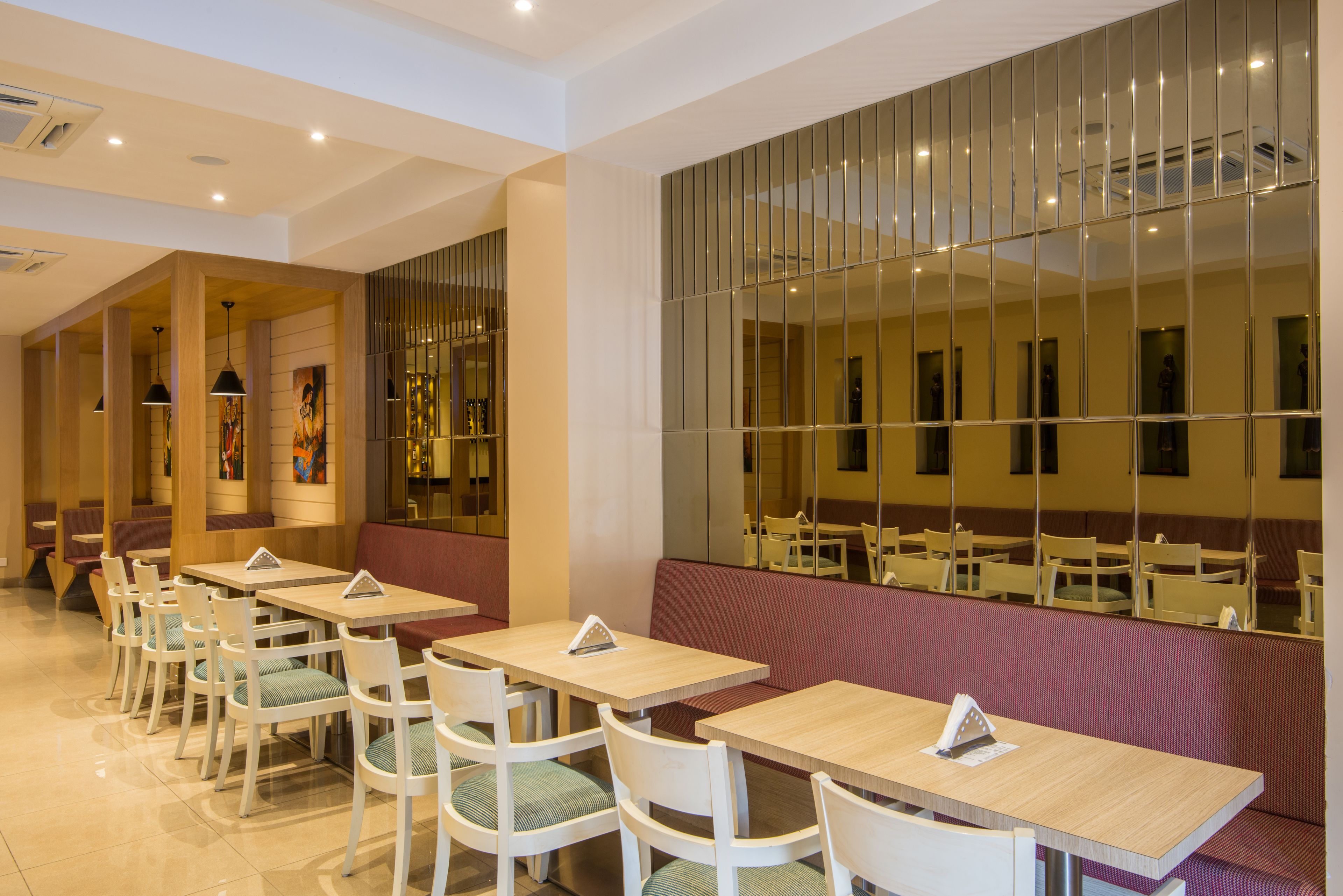 Un restaurante moderno con varias mesas y cabinas, que presenta un diseño de interiores limpio y contemporáneo.