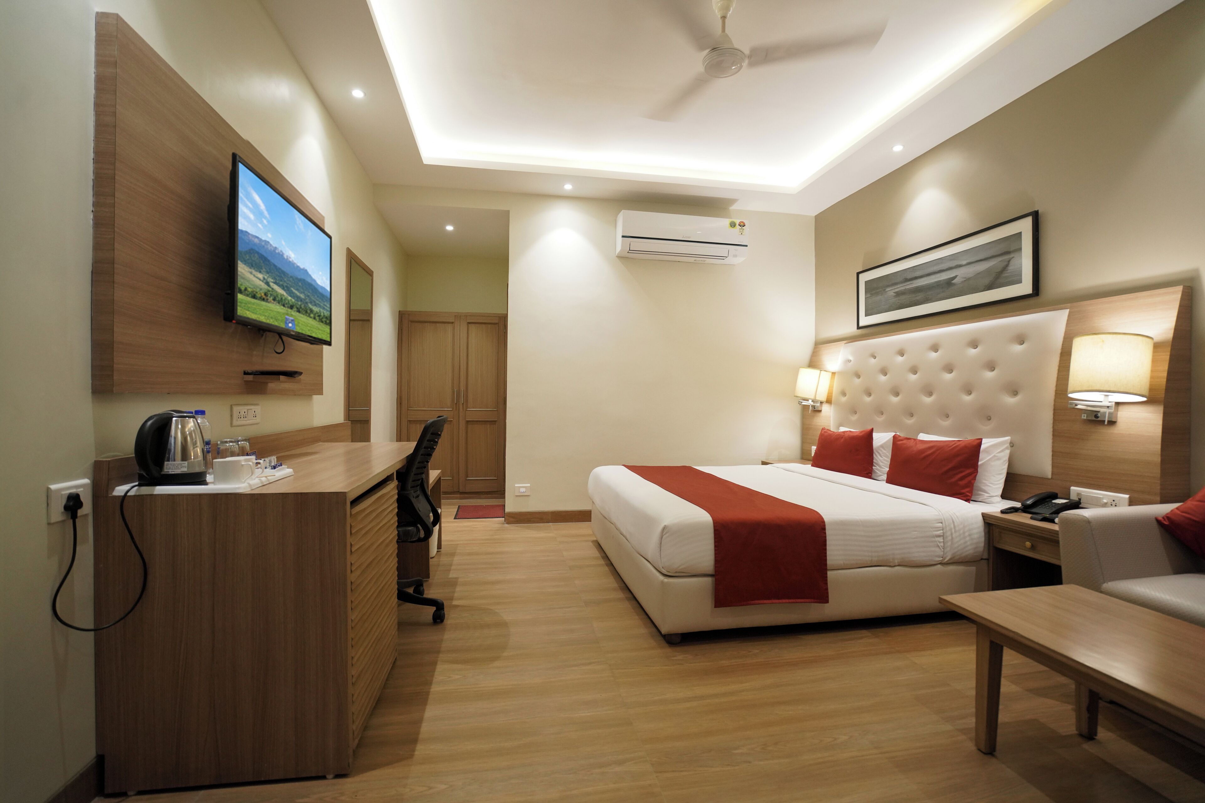 A hotel room with a bed, desk, chair, and a television mounted on the wall.