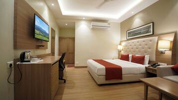 A hotel room with a bed, desk, chair, and a television mounted on the wall.