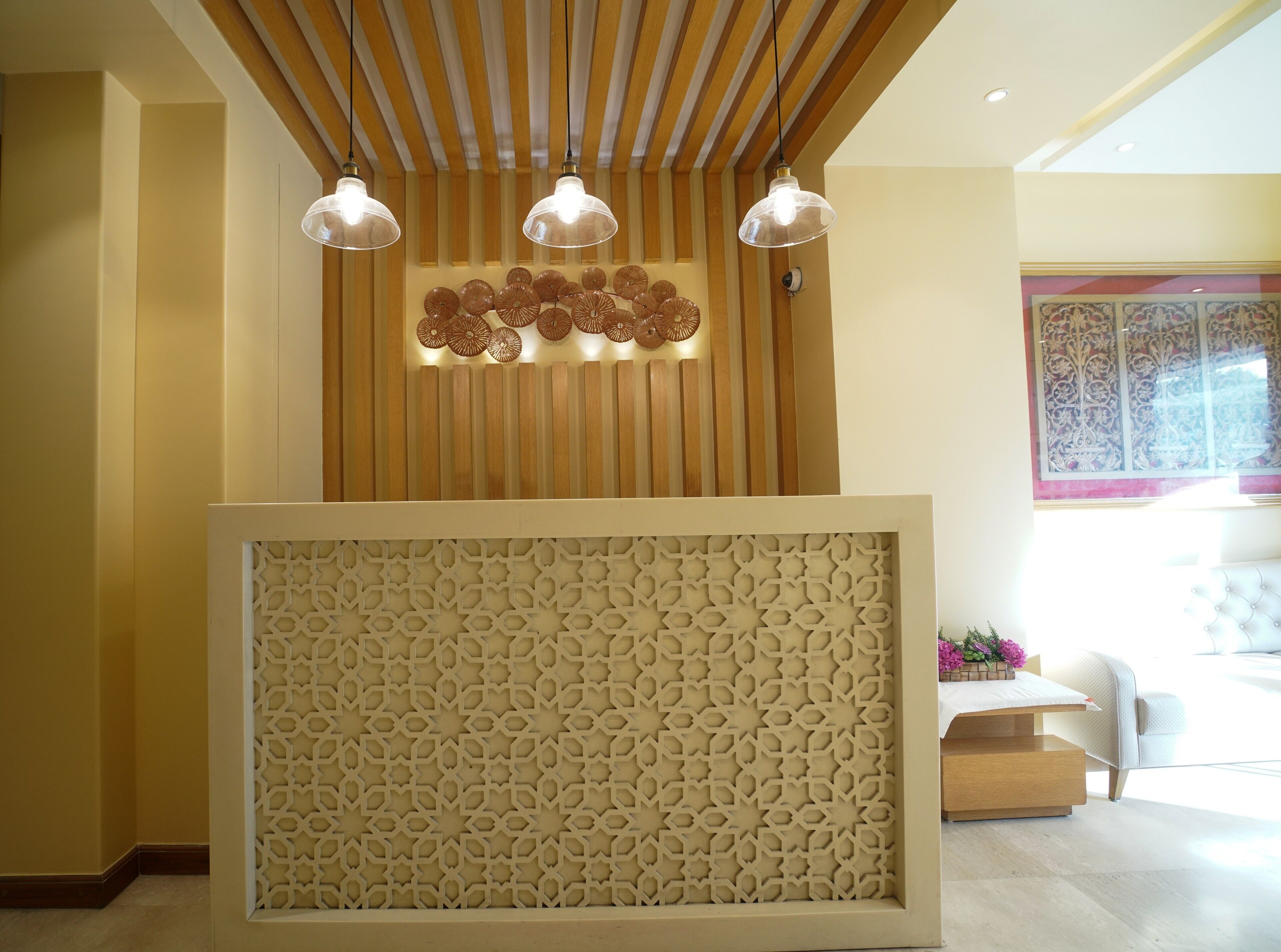 Uma área de recepção com teto de ripas de madeira, painéis decorativos e um painel com padrão.
