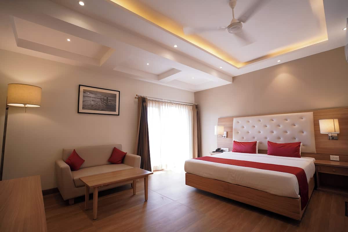 A hotel room with a bed, a sofa, a table, and a lamp.