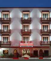 Um hotel com várias varandas, uma placa central com a inscrição "Kalinga Hotel Restaurant & Bar" e uma entrada com carpete vermelho.