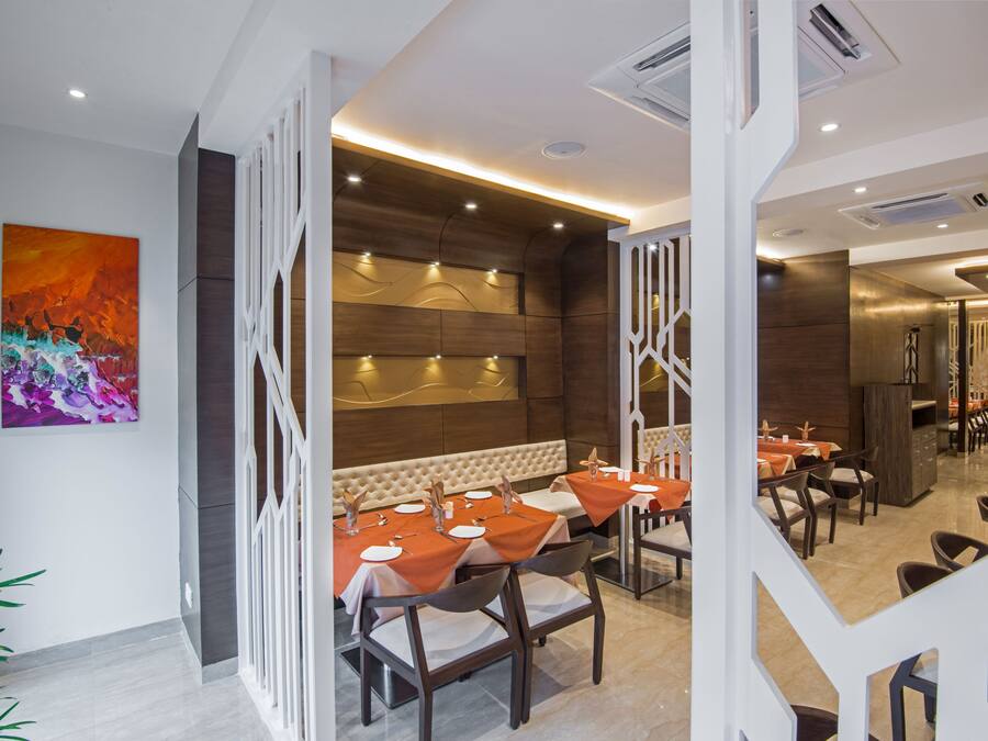 Un restaurante moderno con una zona de asientos central, paneles decorativos blancos y un cuadro abstracto grande en la pared.