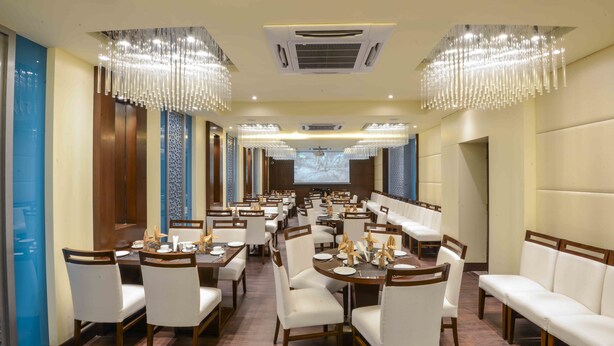 Un amplio comedor con techos altos, candelabros y una pantalla grande para presentaciones.