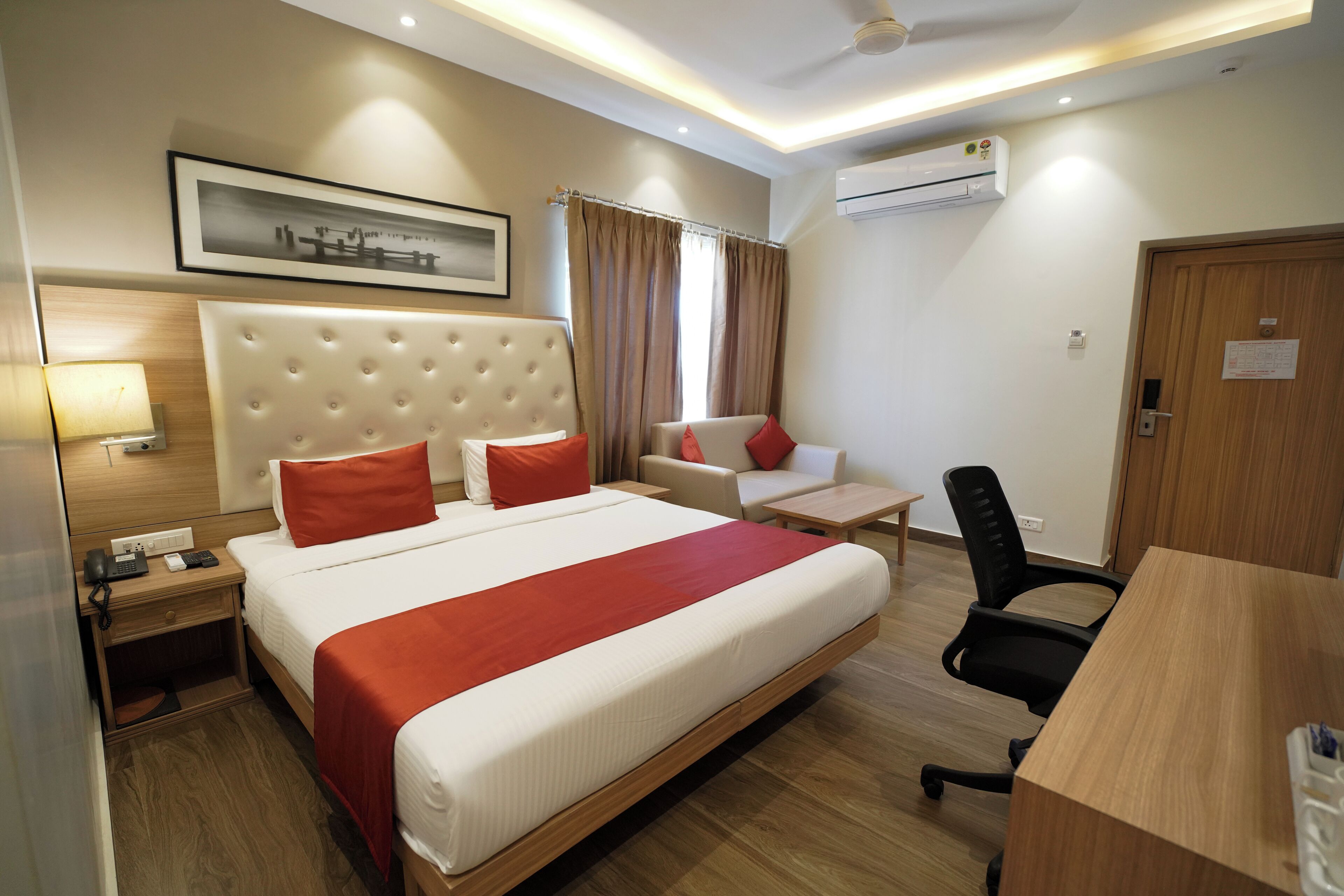 Une chambre d’hôtel avec un grand lit, un bureau, une chaise, une table de chevet avec une lampe et un appareil de climatisation fixé au mur.