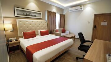 Une chambre d’hôtel avec un grand lit, un bureau, une chaise, une table de chevet avec une lampe et un appareil de climatisation fixé au mur.