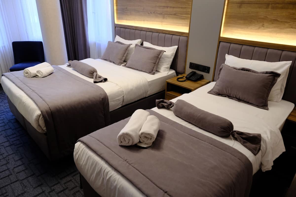 A hotel room with two beds, each with a headboard, bedside tables, and a telephone.