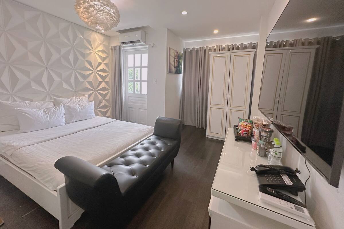 Een moderne slaapkamer met een bed, een zwarte bank, een bureau met telefoon en een kledingkast.