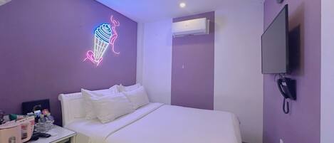 Habitación de hotel con una cama, un letrero de helado de neón, aire acondicionado, televisor y teléfono.