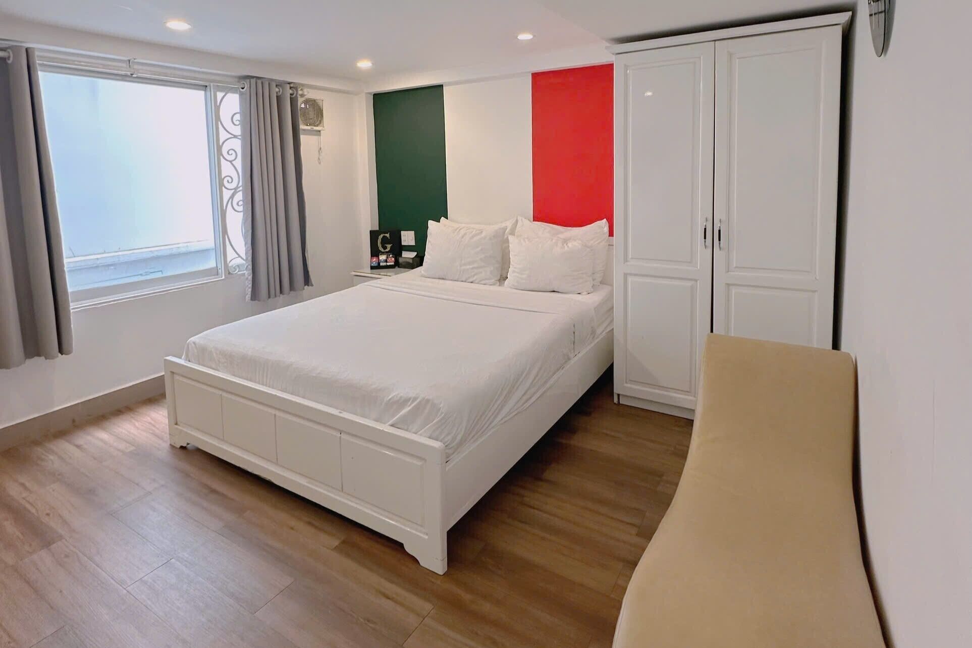 A bedroom with a large bed, a wardrobe, a nightstand, and a window with curtains.