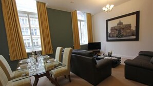 A living room with a glass dining table, two sofas, and a TV.