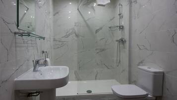 A modern bathroom with a glass-enclosed shower, a white sink, and a toilet.