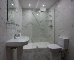 Un baño moderno con ducha de vidrio, lavamanos blanco y un inodoro.